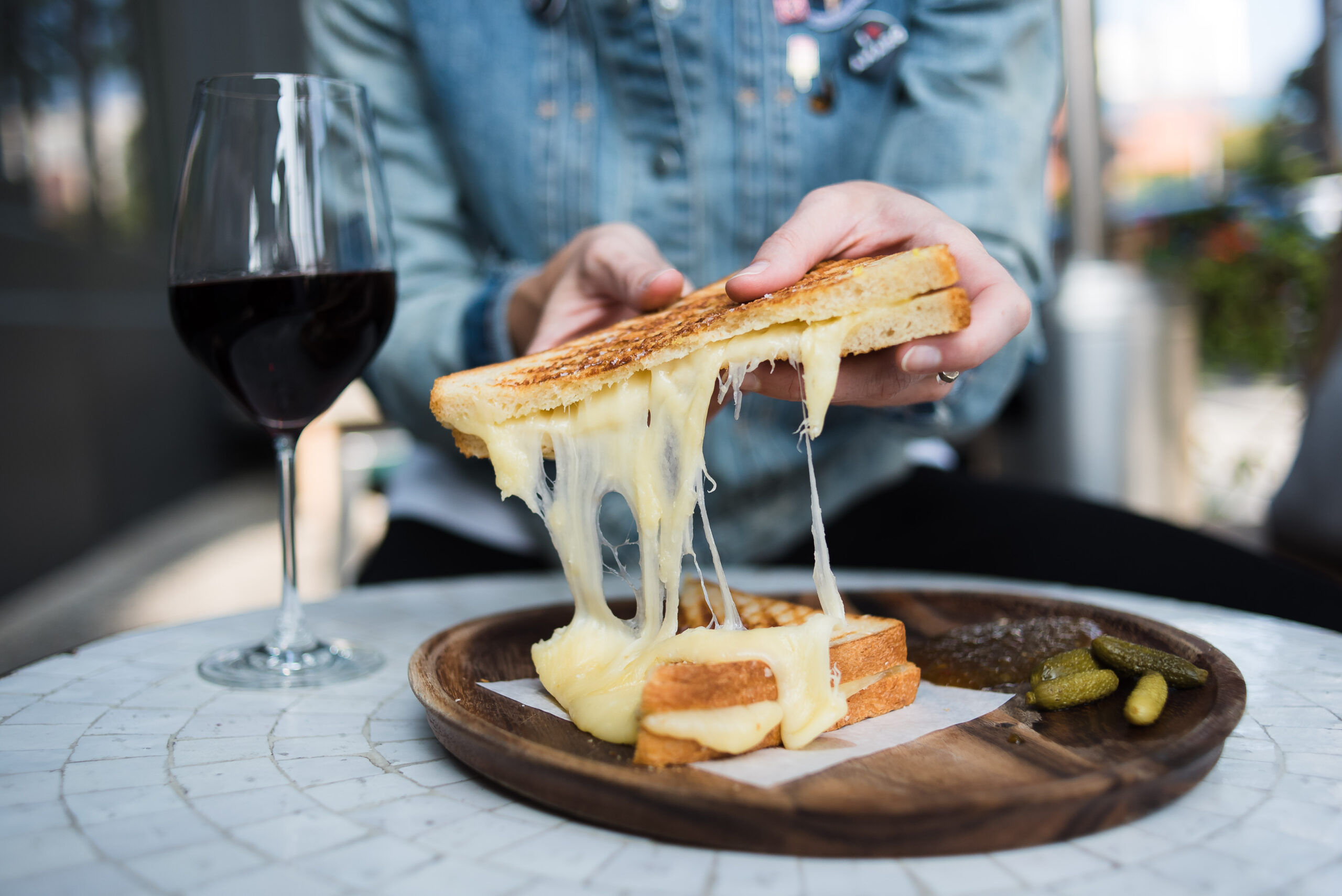 Holding Grilled Cheese with a glass of red wine